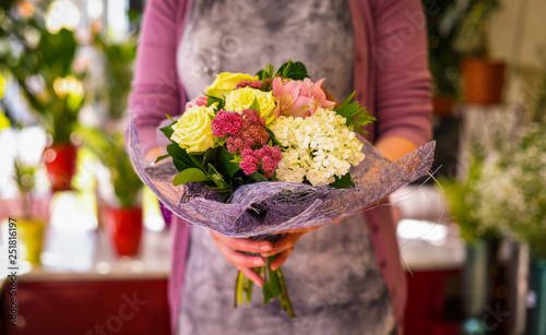 Female florist holding beautiful bouquet at flower shop