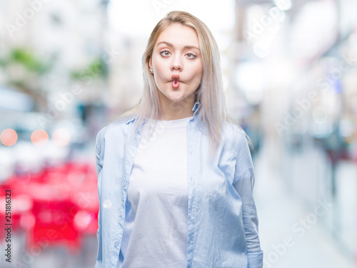 Young blonde woman over isolated background making fish face with lips, crazy and comical gesture. Funny expression. © Krakenimages.com