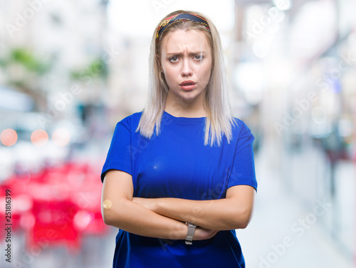 Young blonde woman over isolated background skeptic and nervous, disapproving expression on face with crossed arms. Negative person.