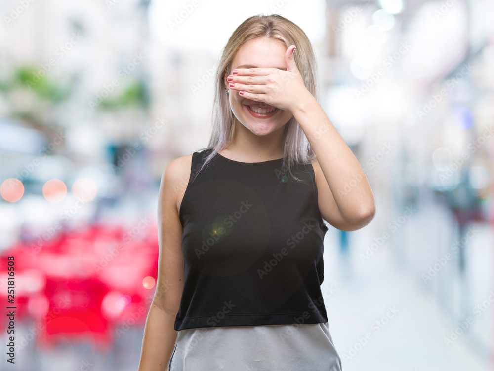 Young blonde woman over isolated background smiling and laughing with hand on face covering eyes for surprise. Blind concept.
