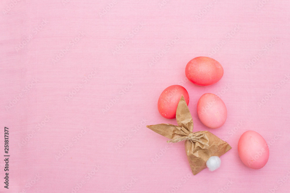Easter bunny (rabbit) paper gift egg wrapping idea. Handicraft (homemade) concept for children (kids). On pink cloth (linen) background, top view Easter bunny (rabbit) paper gift egg wrapping idea. Handicraft (homemade) concept for children (kids). On pink cloth (linen) background, top view