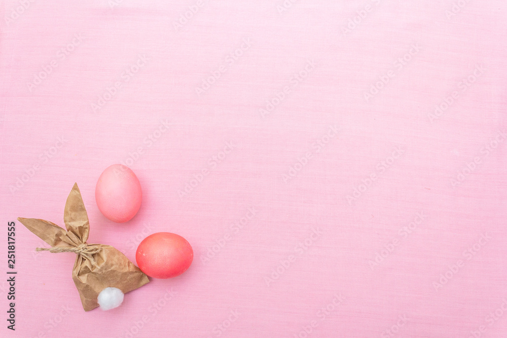 Easter bunny (rabbit) paper gift egg wrapping idea. Handicraft (homemade) concept for children (kids). On pink cloth (linen) background, top view