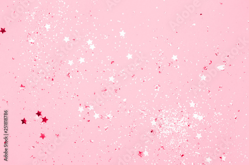 Pink confetti and stars and sparkles on pink background. Top view, flat lay. Copyspace for text. Bright and festive holiday background. For Christmas, New year, Mother's day.