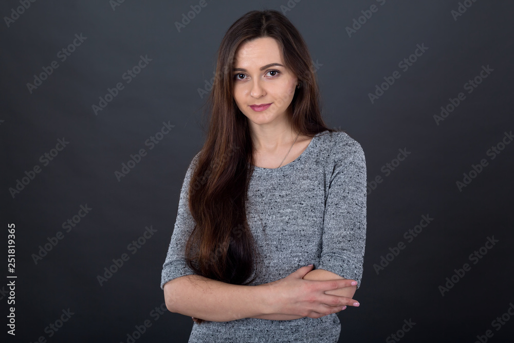 Portrait of a young brunette woman with long hair on a gray background. Portrait of a young brunette woman with long hair on a gray background.