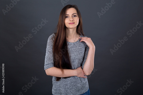 Portrait of a young brunette woman with long hair on a gray background. © A Stock Studio
