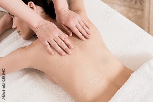cropped view of masseur doing back massage to attractive woman