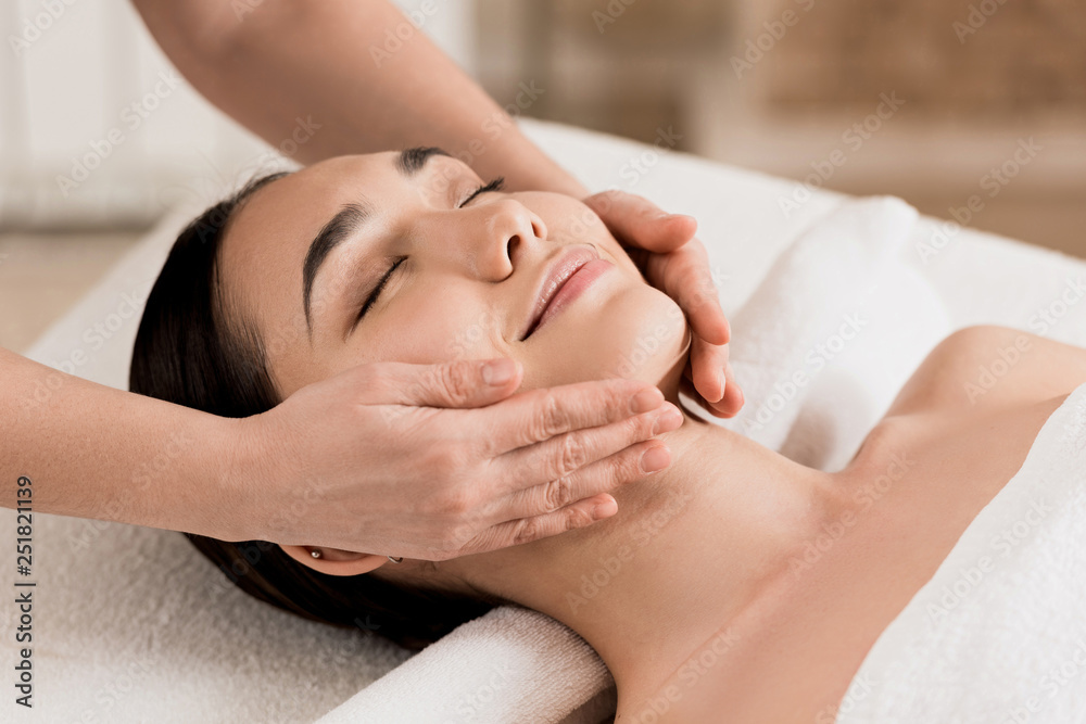 woman getting face massage with closed eyes at spa woman getting face massage with closed eyes at spa