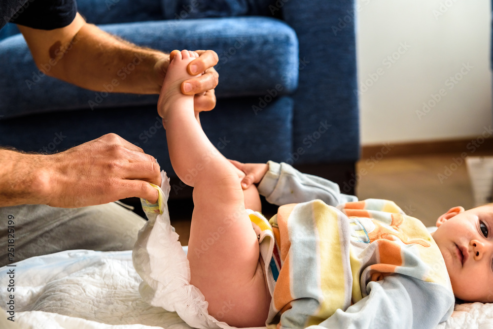 Φωτογραφία A father involved in taking care of his children by changing his daughter's dirty diaper