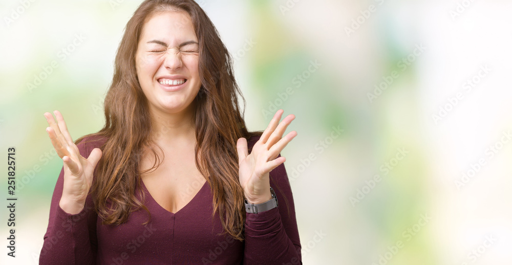 Beautiful and attractive plus size young woman wearing a dress over isolated background celebrating mad and crazy for success with arms raised and closed eyes screaming excited. Winner concept Beautiful and attractive plus size young woman wearing a dress over isolated background celebrating mad and crazy for success with arms raised and closed eyes screaming excited. Winner concept