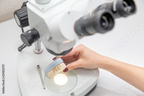 dentures are held in hands and examined in a microscope