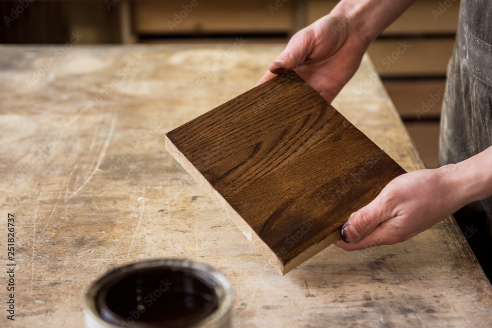 Carpenter painting wooden board in a wooden workshop. Profession, carpentry and woodwork concept. Carpenter painting wooden board in a wooden workshop. Profession, carpentry and woodwork concept.
