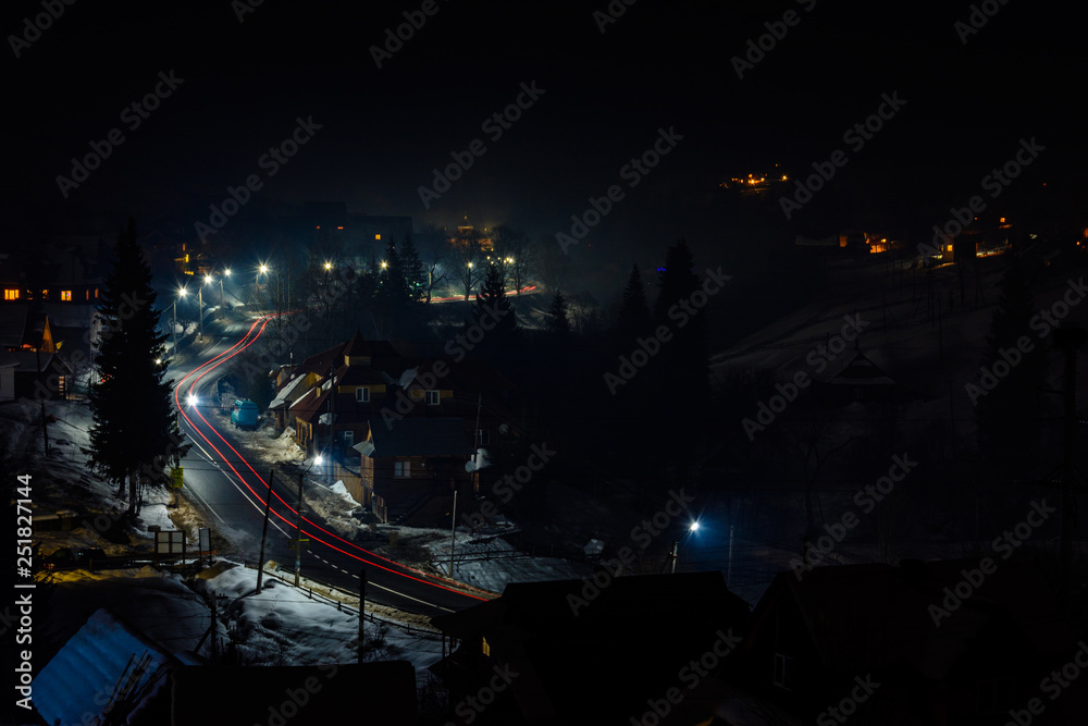 Magnificent night landscape of the Ukrainian village in bright light and blurred automobile lights