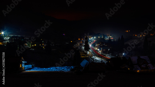 A wonderful panorama of the night mountain village of Ukraine with car tracks