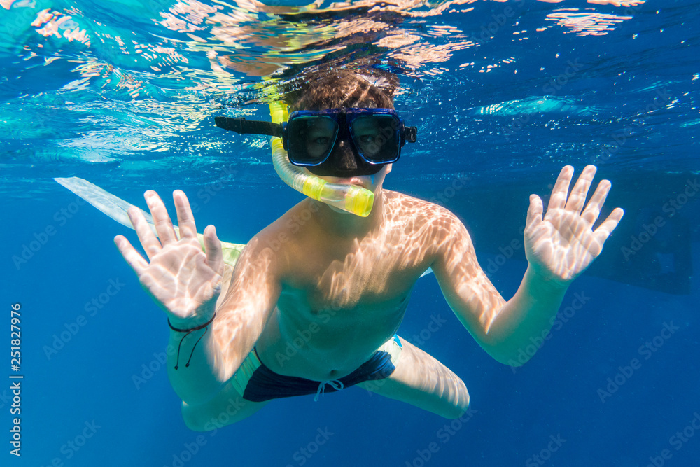 Boy in swimming mask dive in Red sea near yacht