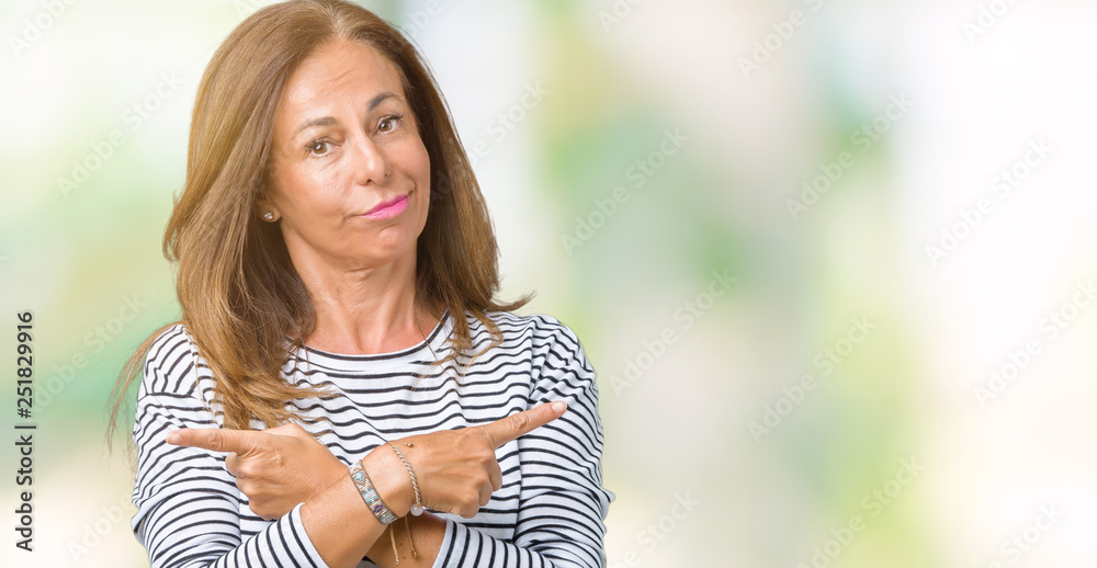 Beautiful middle age woman wearing stripes sweater over isolated background Pointing to both sides with fingers, different direction disagree