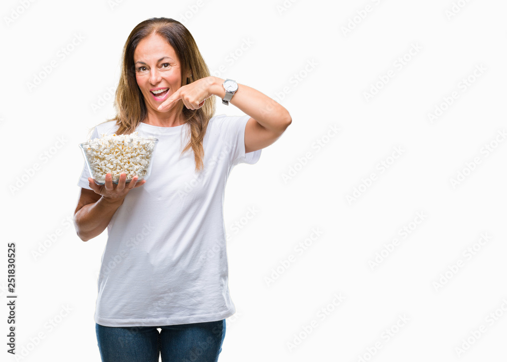 Middle age hispanic woman eating popcorn over isolated background very happy pointing with hand and finger Middle age hispanic woman eating popcorn over isolated background very happy pointing with hand and finger