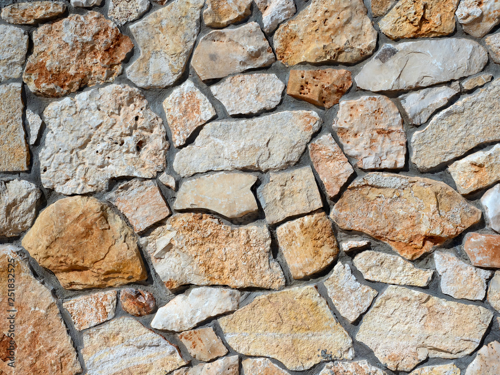 Wall of raw natural stone shades of brown.reinforced with cement Wall of raw natural stone shades of brown.reinforced with cement