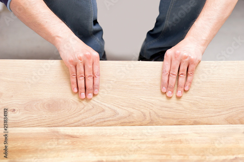 hands laying yellow laminate flooring