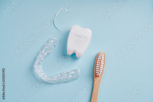 Ecological bamboo toothbrush, mouth guard and dental floss on blue photo