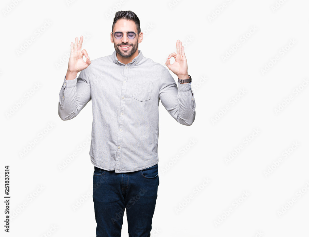 Young handsome man wearing sunglasses over isolated background relax and smiling with eyes closed doing meditation gesture with fingers. Yoga concept. Young handsome man wearing sunglasses over isolated background relax and smiling with eyes closed doing meditation gesture with fingers. Yoga concept.