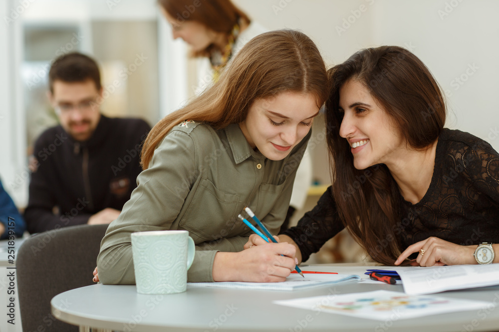© Nestor - Students talking with each other during interesting lectures. Beautiful girls sitting on lessons and working under exercises. Happy pupils enjoying their courses in private school of foreign language.