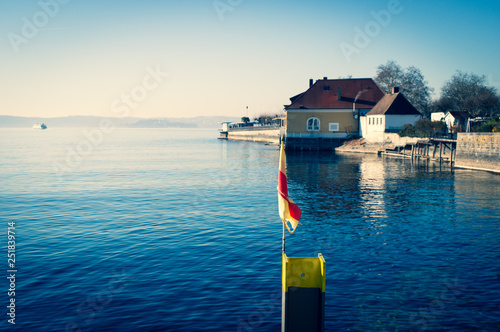 Jetty in Meersburg at Lake Constance in Germany with flag and blue water photo