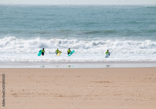 surfers with boards go catching the wave