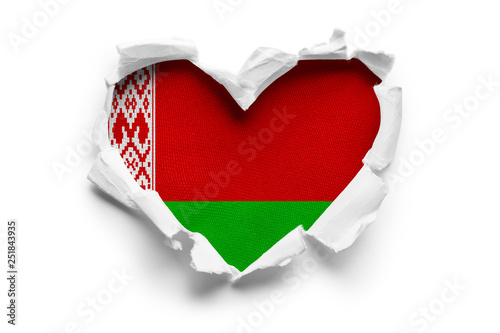 Heart shaped hole torn through paper, showing satin texture of flag of Belarus. Isolated on white background