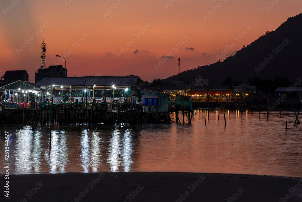 Seafood restaurant on piles with a red colored sunset in background.