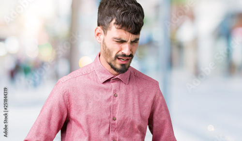 Young handsome man wearing pink shirt over isolated background with hand on stomach because indigestion, painful illness feeling unwell. Ache concept.