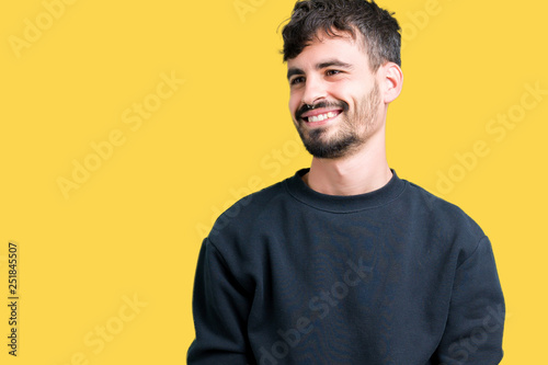 Young handsome man over isolated background looking away to side with smile on face, natural expression. Laughing confident.