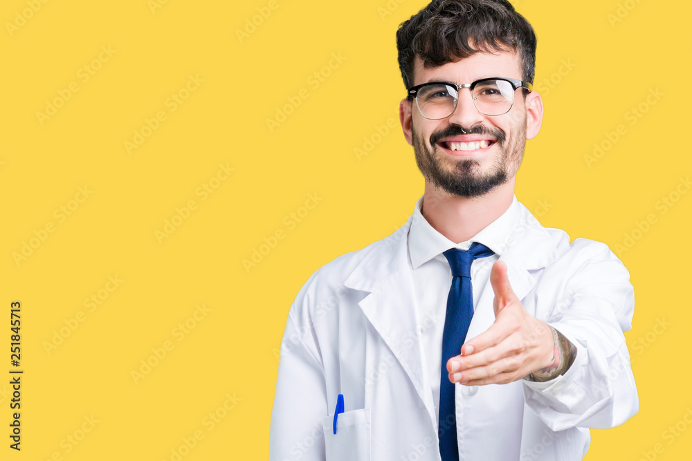 Young professional scientist man wearing white coat over isolated background smiling friendly offering handshake as greeting and welcoming. Successful business. Young professional scientist man wearing white coat over isolated background smiling friendly offering handshake as greeting and welcoming. Successful business.