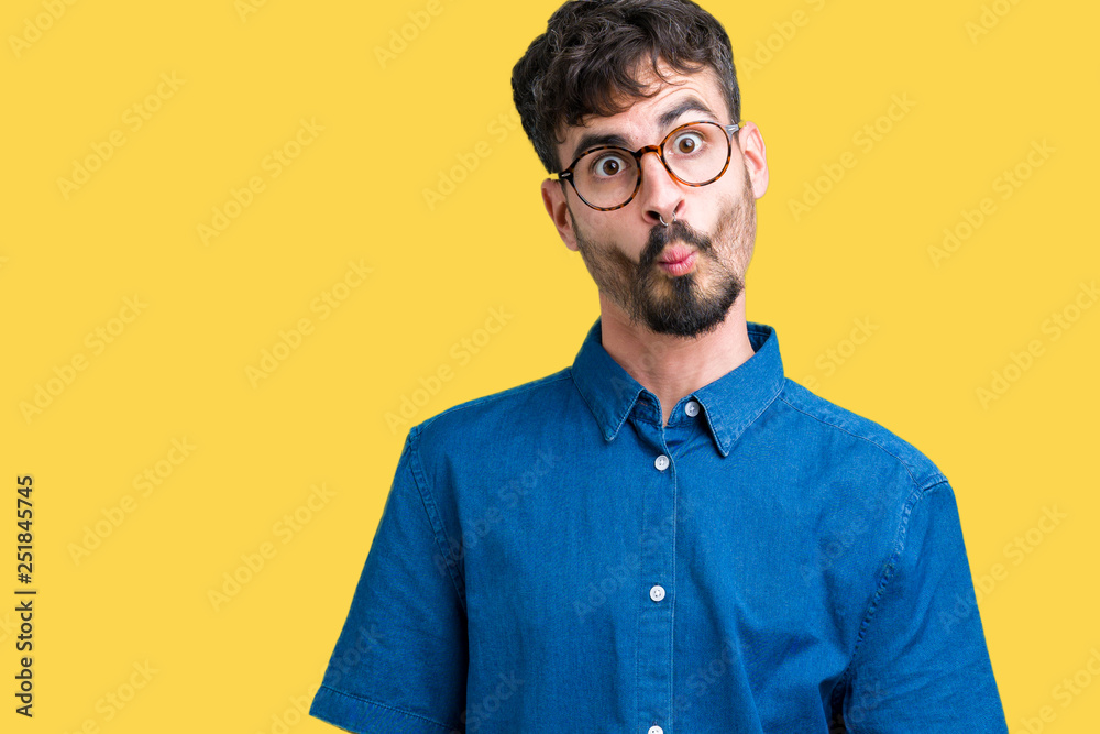 Fototapeta premium Young handsome man wearing glasses over isolated background making fish face with lips, crazy and comical gesture. Funny expression.