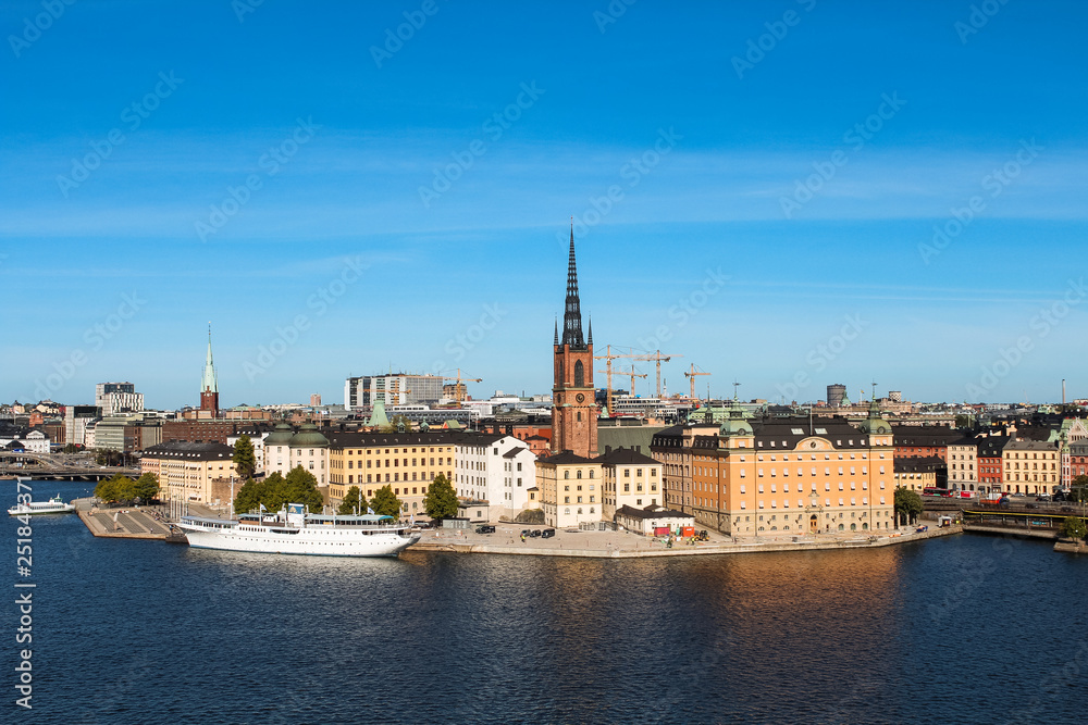 View onto Gamla Stan with Riddarholmskyrkan and a white large ship as seen from Södermalm during summer (Stockholm, Sweden, Europe)