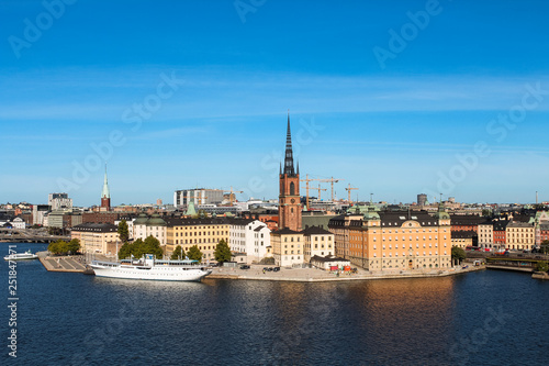 View onto Gamla Stan with Riddarholmskyrkan and a white large ship as seen from Södermalm during summer (Stockholm, Sweden, Europe)