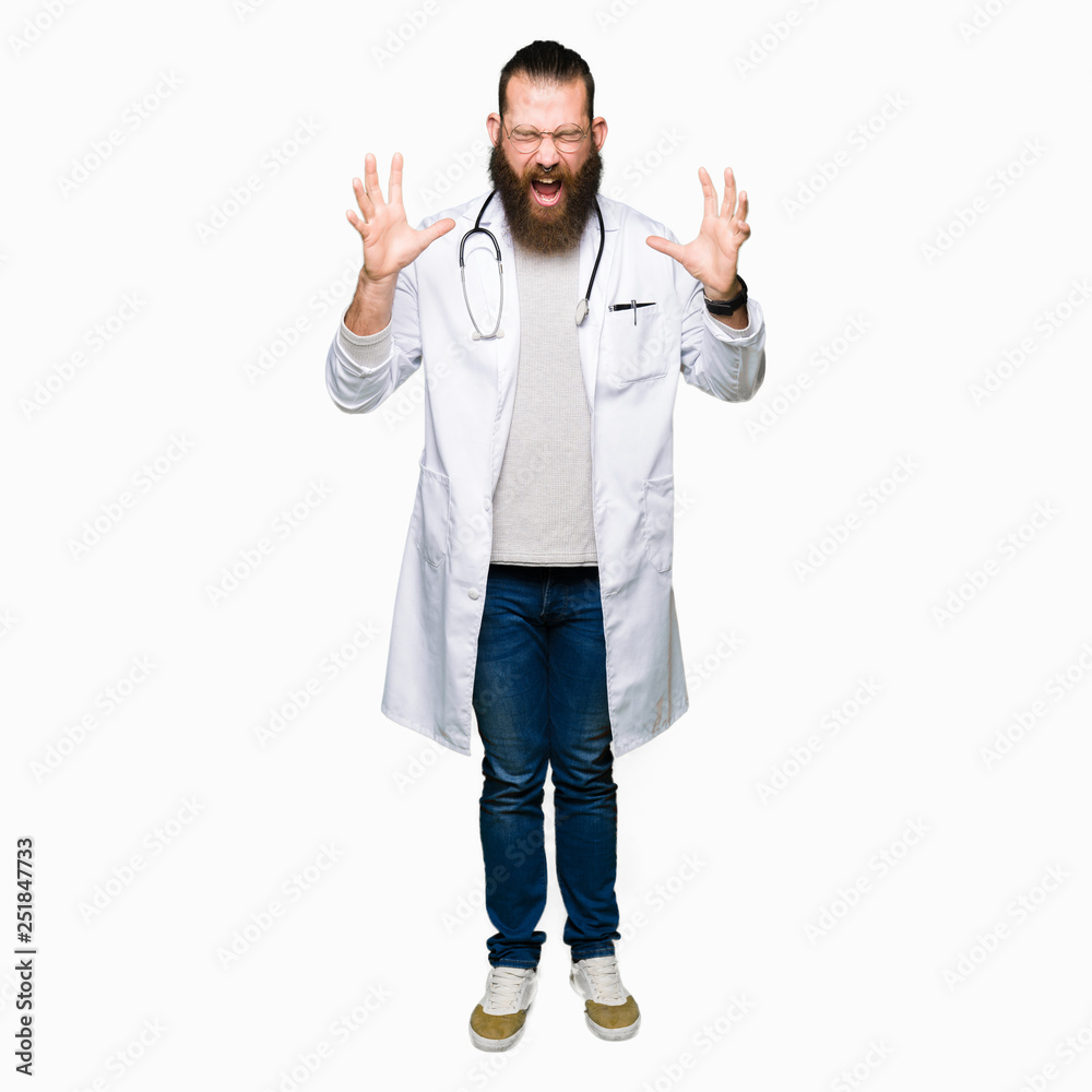 Young blond doctor man with beard wearing medical coat celebrating mad and crazy for success with arms raised and closed eyes screaming excited. Winner concept Young blond doctor man with beard wearing medical coat celebrating mad and crazy for success with arms raised and closed eyes screaming excited. Winner concept