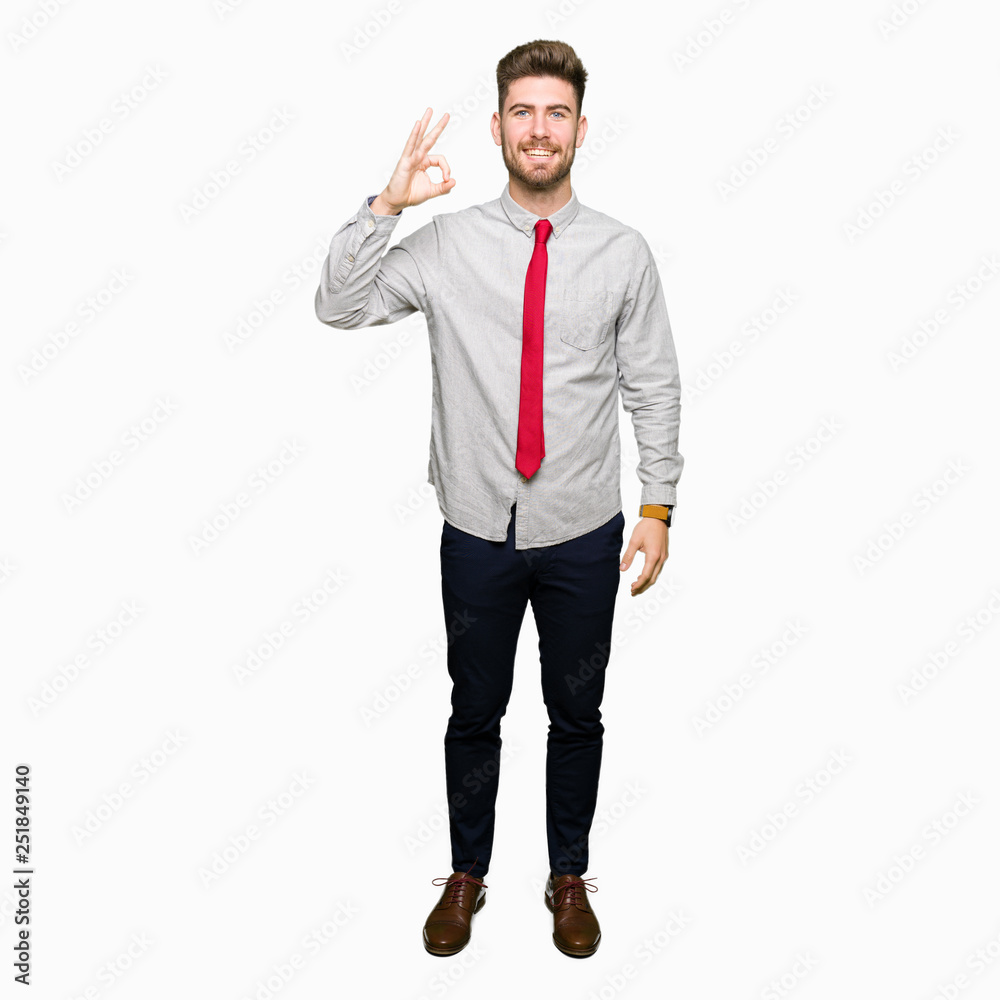 Young handsome business man smiling positive doing ok sign with hand and fingers. Successful expression.