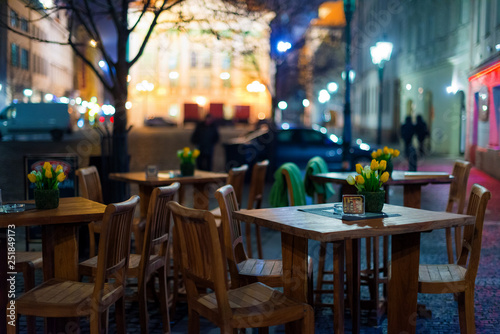 Fototapeta Naklejka Na Ścianę i Meble -  Outdoor restaurant with wooden tables on the European square. Empty outdoor Cafe. Blurred background.