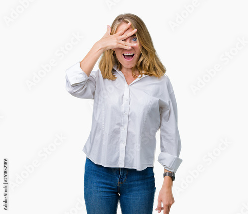 Beautiful young business woman over isolated background peeking in shock covering face and eyes with hand, looking through fingers with embarrassed expression.