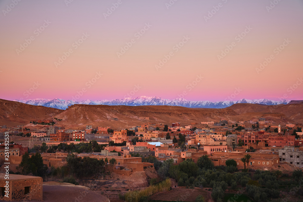 Beautiful sunrise over the snow covered Atlas mountains and a city near Ait Ben Haddou fort in Morocco, Africa