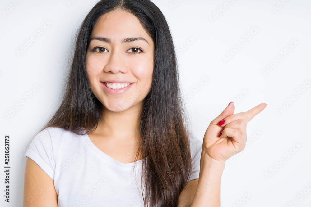 Beautiful brunette woman over isolated background with a big smile on face, pointing with hand and finger to the side looking at the camera. Beautiful brunette woman over isolated background with a big smile on face, pointing with hand and finger to the side looking at the camera.