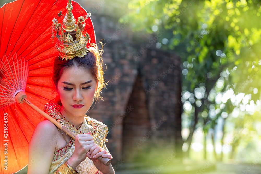 Thai Woman In Traditional Costume with umbrella of Thailand. Female  Traditional Costume with thai style temple background. Wat Chaiwatthanaram temple in Ayuthaya is Unesco World Heritage.