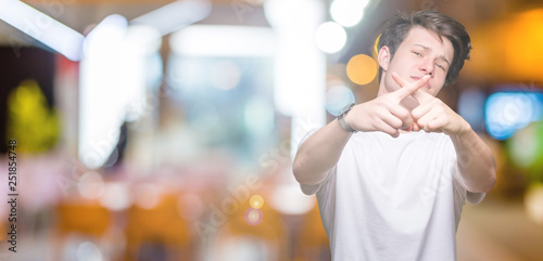 Young handsome man wearing casual white t-shirt over isolated background Rejection expression crossing fingers doing negative sign