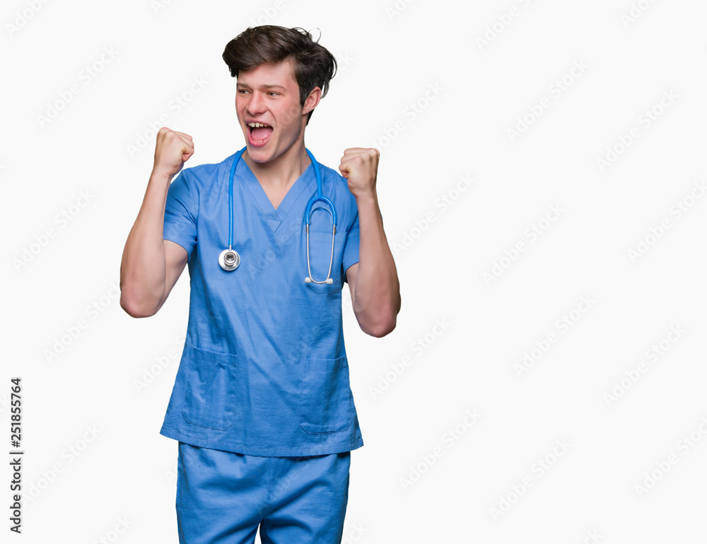 Young doctor wearing medical uniform over isolated background celebrating surprised and amazed for success with arms raised and open eyes. Winner concept. Young doctor wearing medical uniform over isolated background celebrating surprised and amazed for success with arms raised and open eyes. Winner concept.