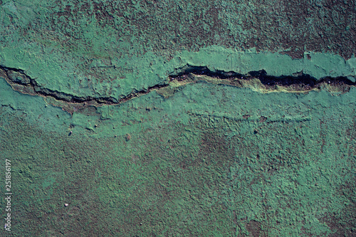 Green painted asphalt with earthquake crack photo. Cement floor stain and grit closeup. Urban texture.
