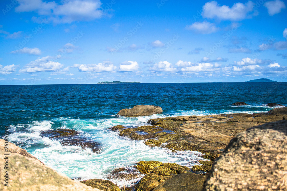 Beautiful landscapes of the coasts of Brazil, with a beautiful blue sky and crystalline waters, accompanied by rocks and green trees