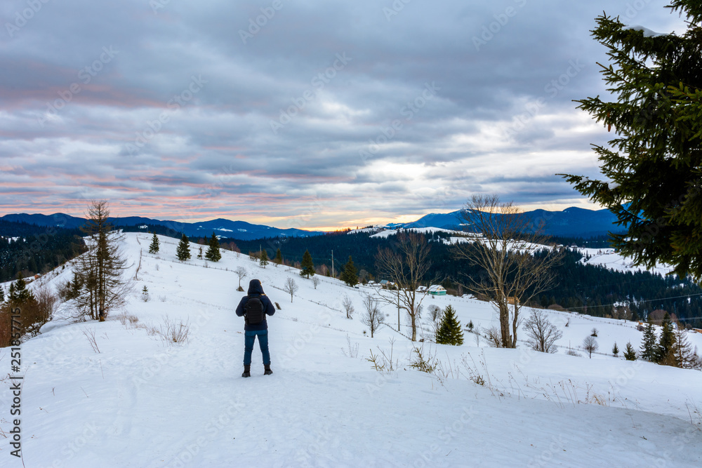 Traveling photographer admires the beautiful sunrise on the top of Carpathian mountains