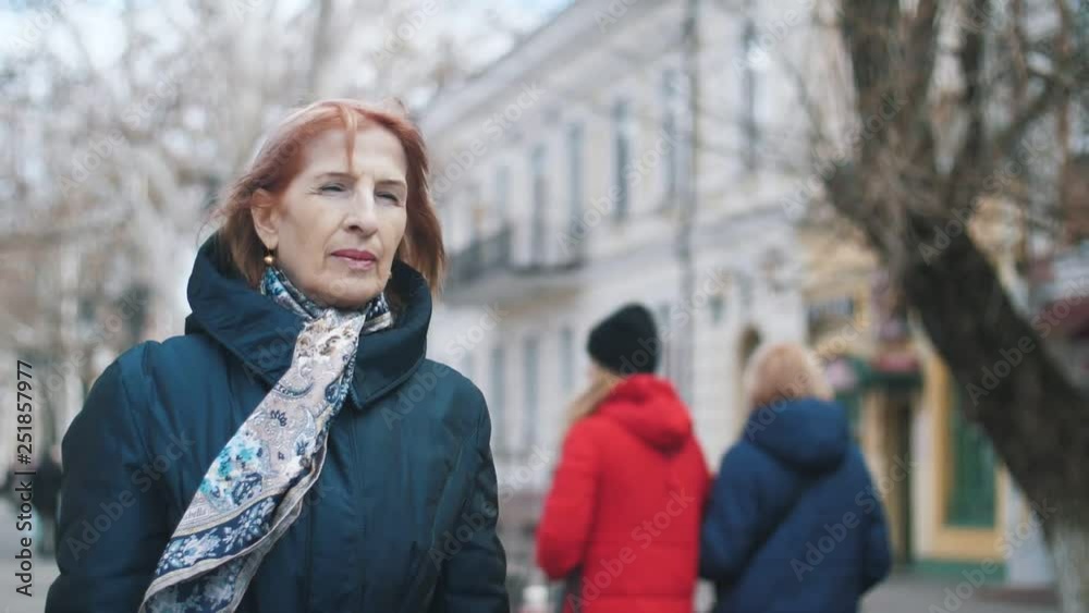 Confident senior woman smiling and walking in a street in winter in slow motion Confident senior woman smiling and walking in a street in winter in slow motion