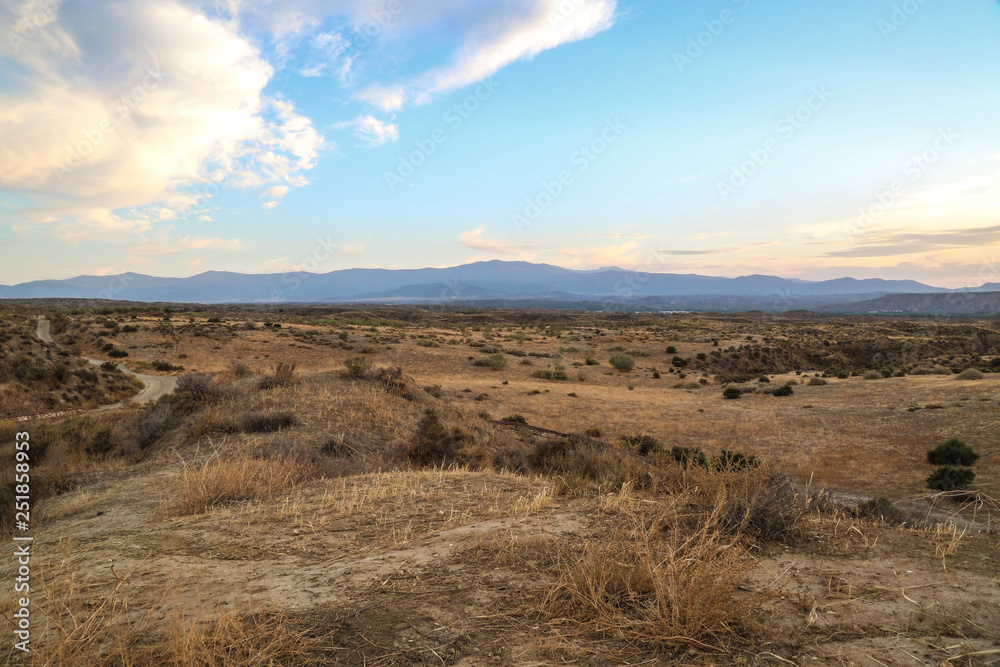 landscape with steppe grassland mountains and clouds at a blue sky