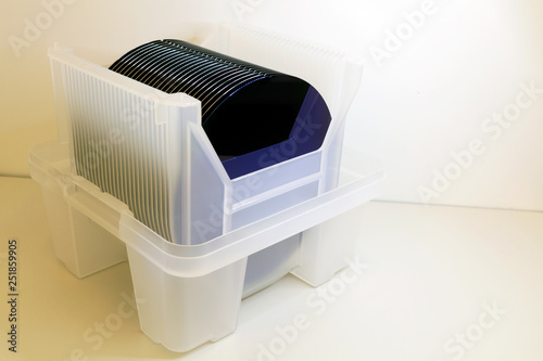 Silicon Wafers in white plastic holder box on a table- A wafer is a thin slice of semiconductor material, such as a crystalline silicon, used in electronics for the fabrication of integrated circuits. photo